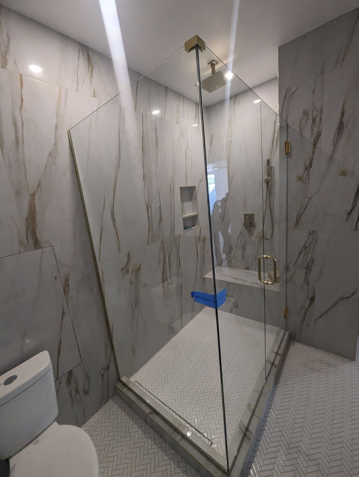 A bathroom with a toilet and a walk in shower with a glass door.