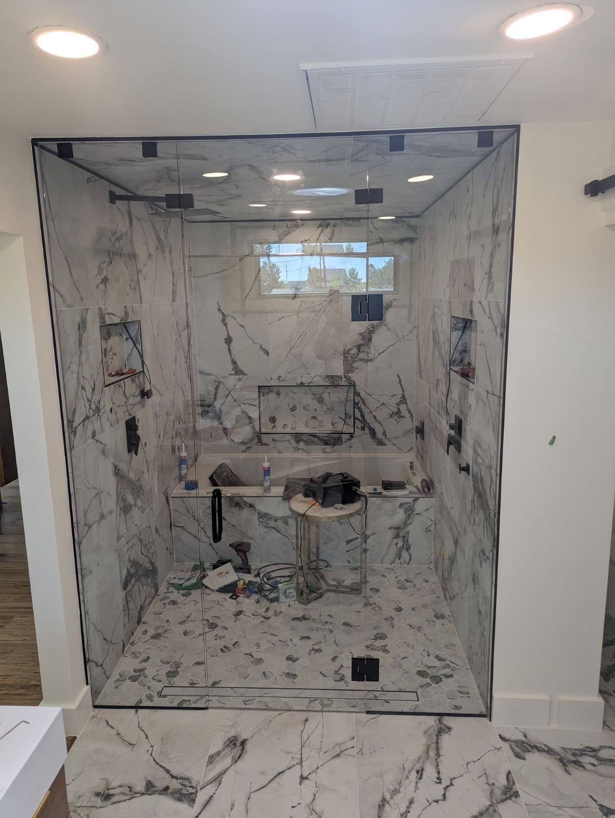 A bathroom with marble tiles and a walk in shower with a glass door.