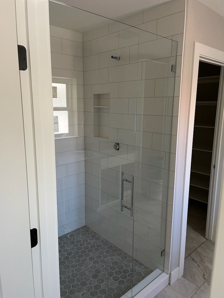 A bathroom with a walk in shower with a glass door.