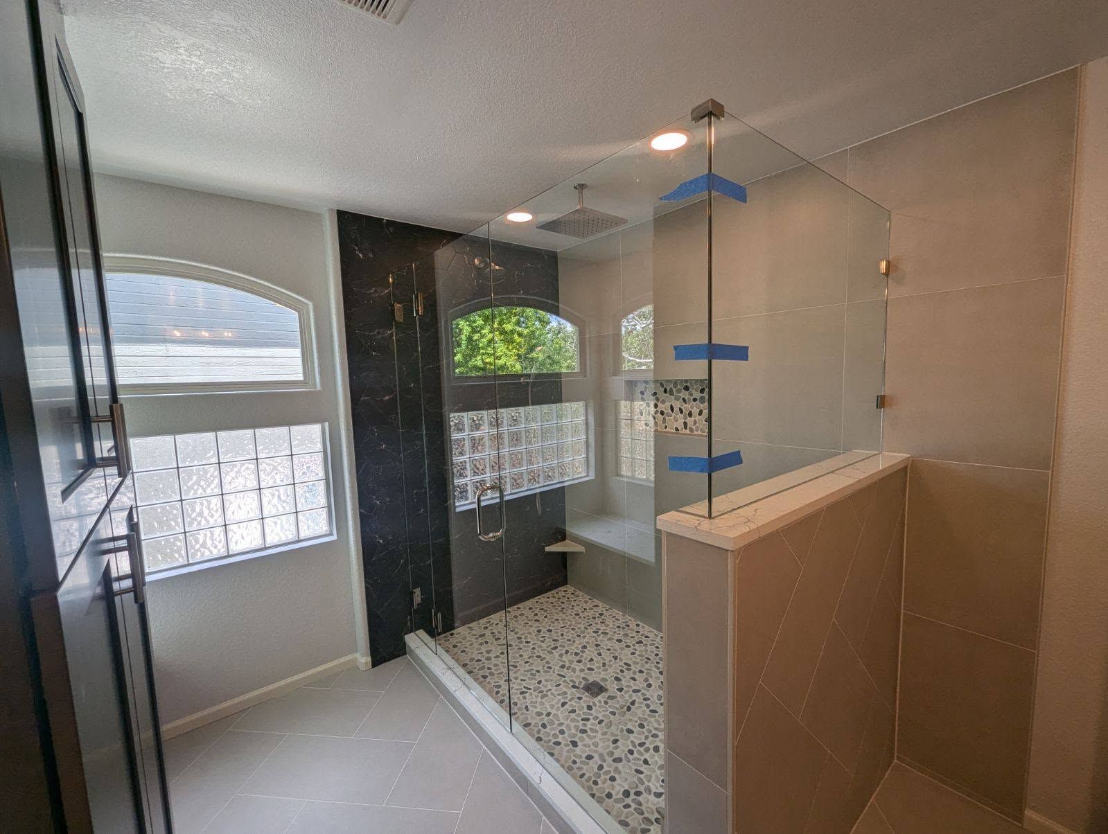 A bathroom with a walk in shower and a window.