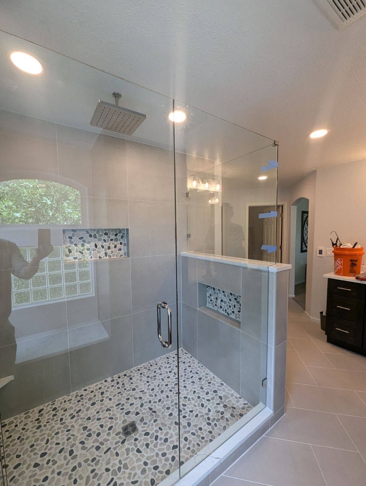 A bathroom with a walk in shower with a glass door.