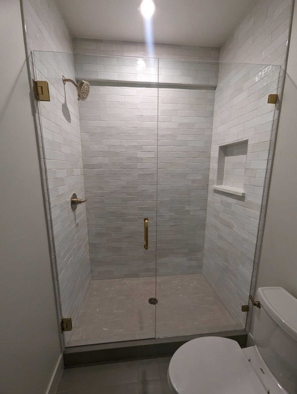 A bathroom with a toilet and a shower with a glass door.
