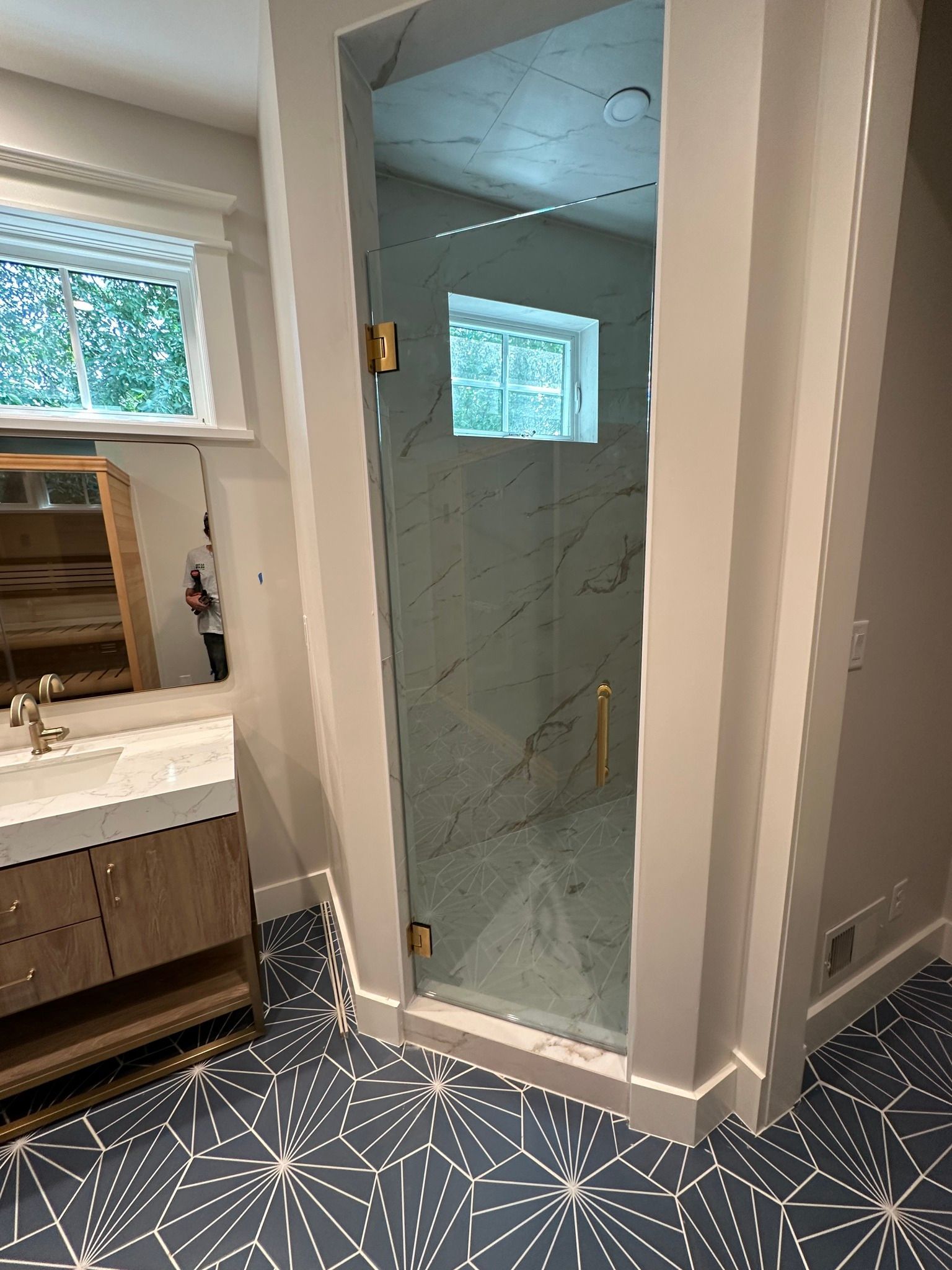 A bathroom with a glass shower door and a sink.