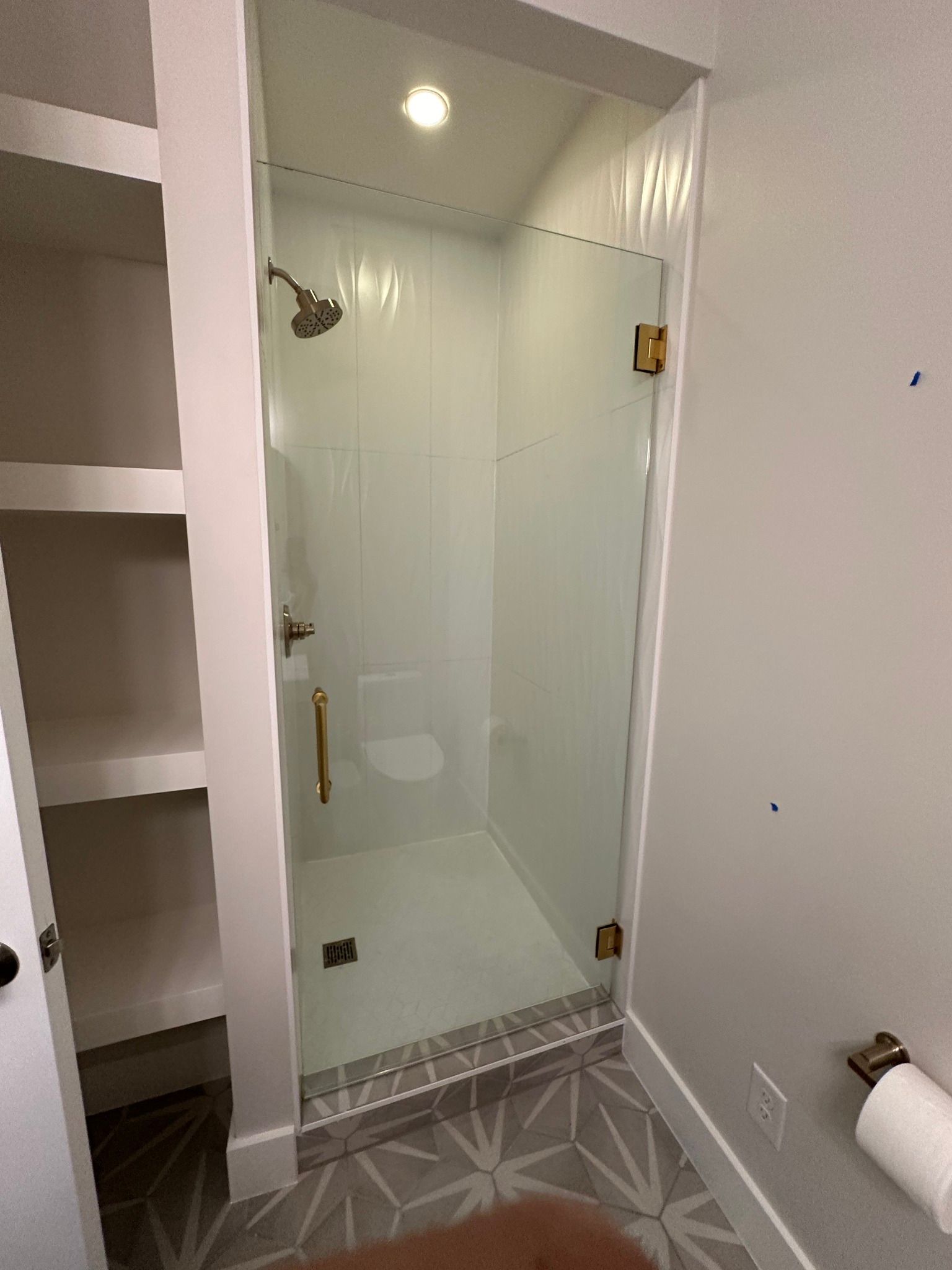 A bathroom with a glass shower door and a toilet.