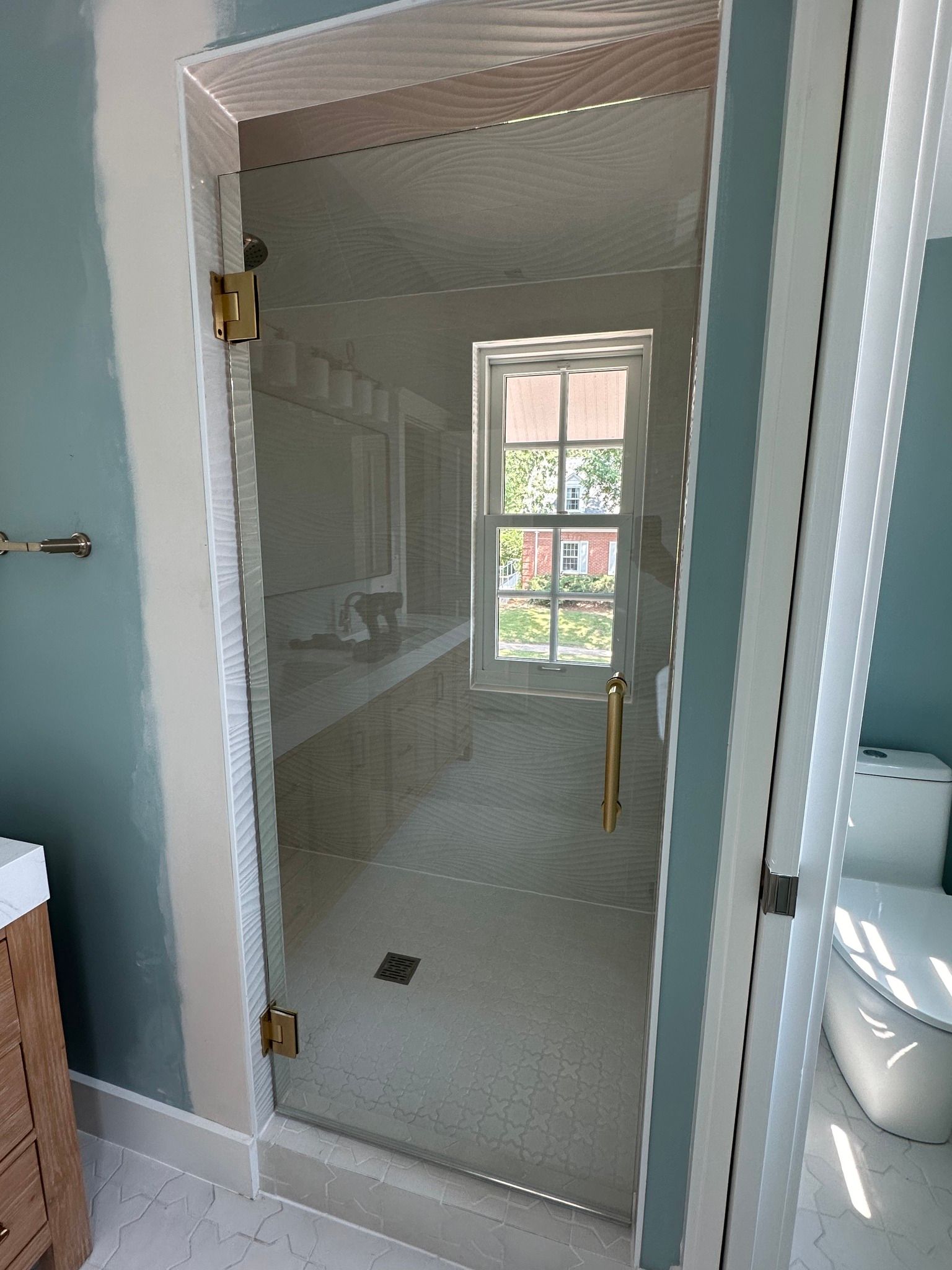 A bathroom with a glass shower door and a window.
