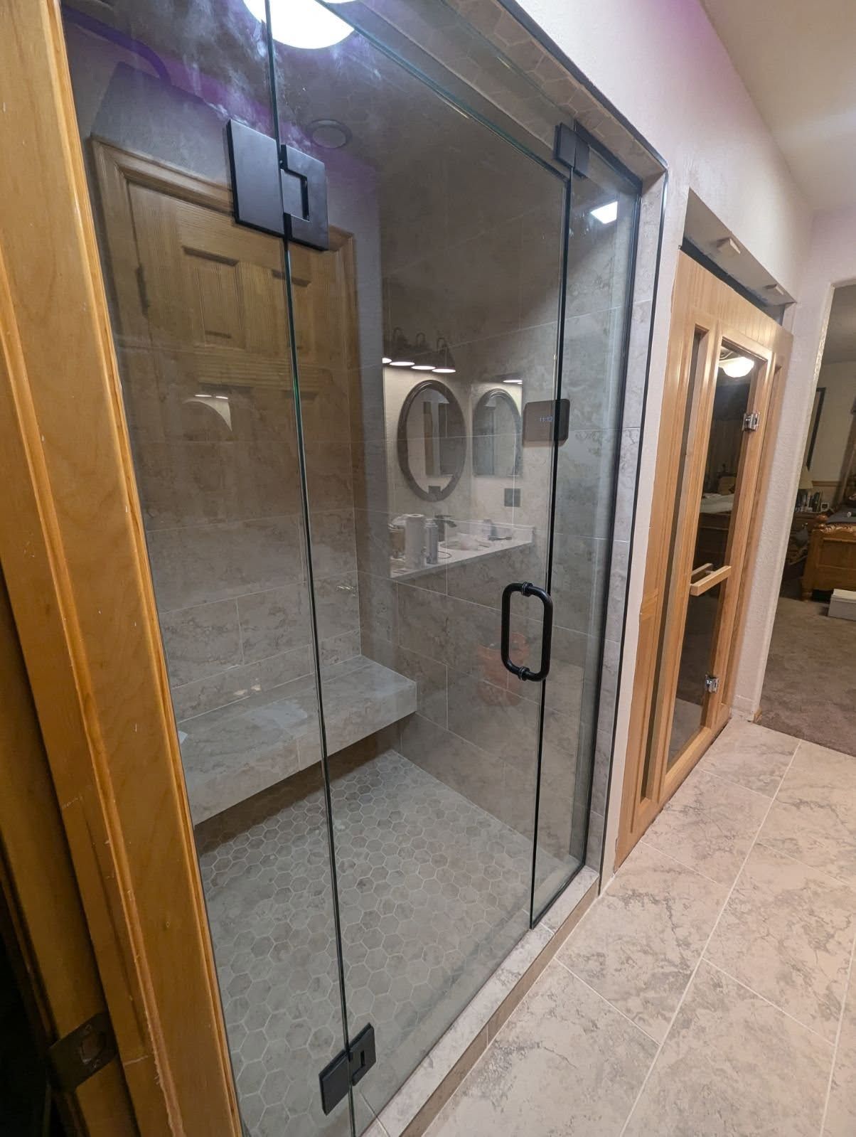 A bathroom with a walk in shower and a glass door.