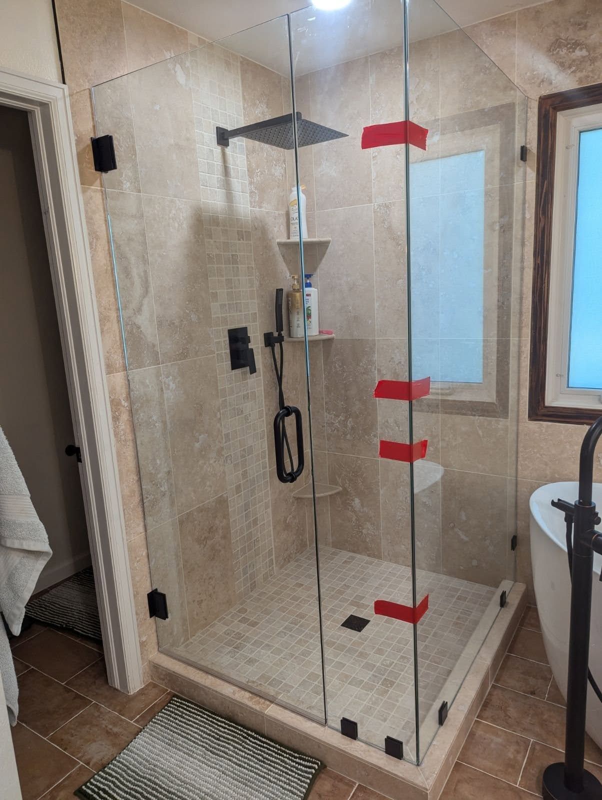 A bathroom with a walk in shower and a tub.