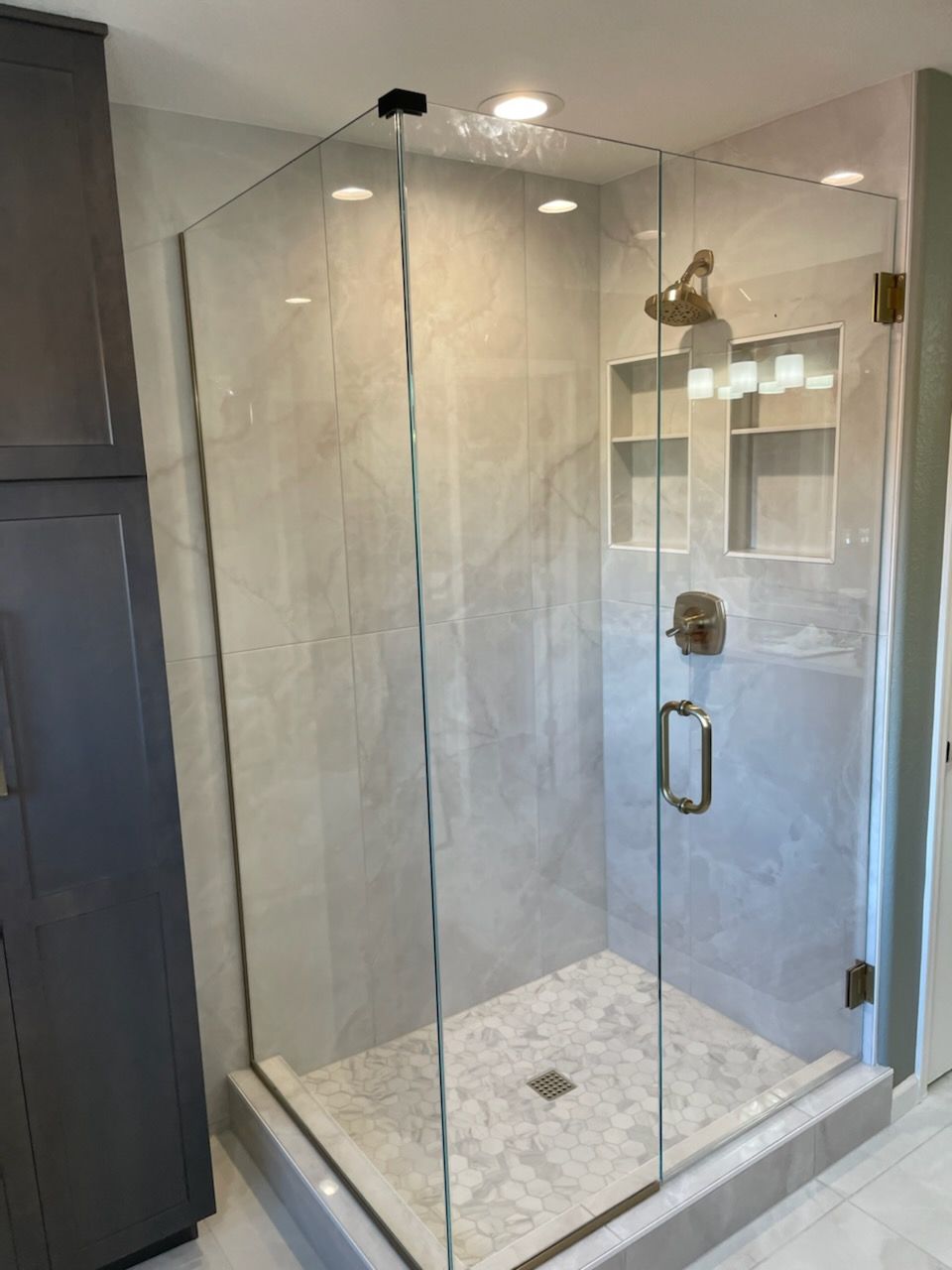 A bathroom with a walk in shower with a glass door.