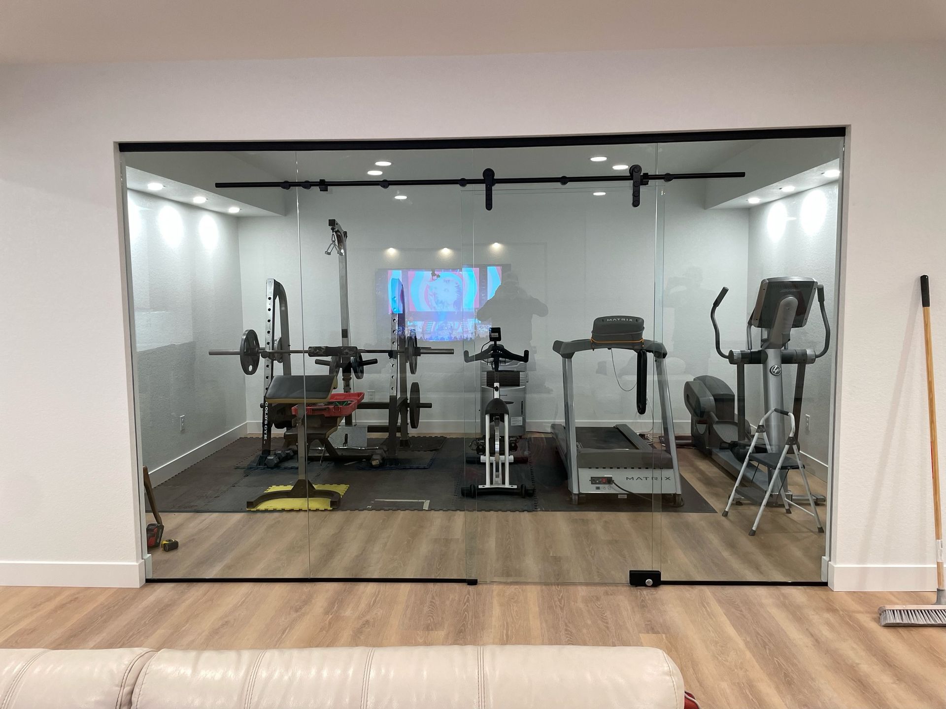A home gym with a treadmill , exercise bike , and barbells.