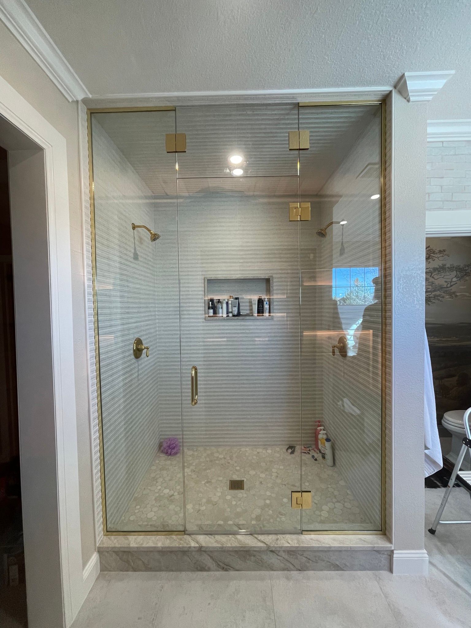 A bathroom with a walk in shower with a glass door.