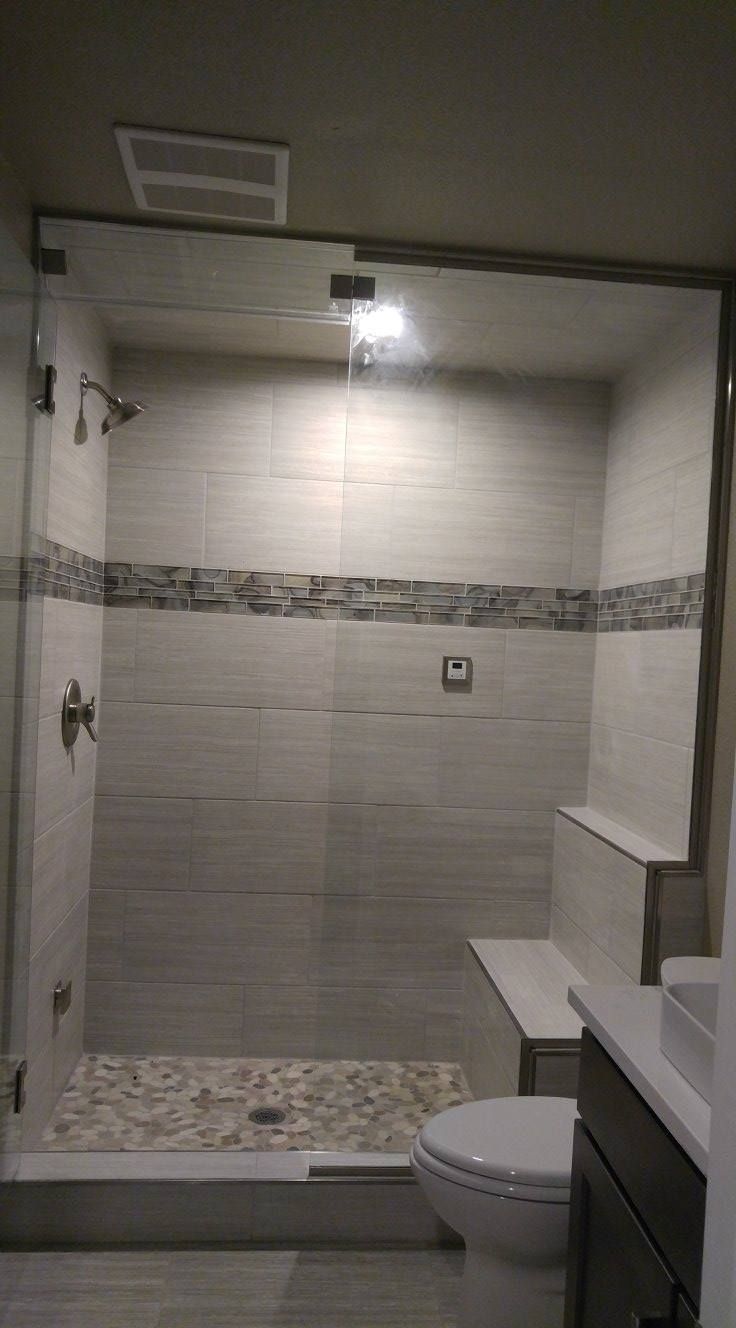 A bathroom with a walk in shower , toilet , sink and mirror.