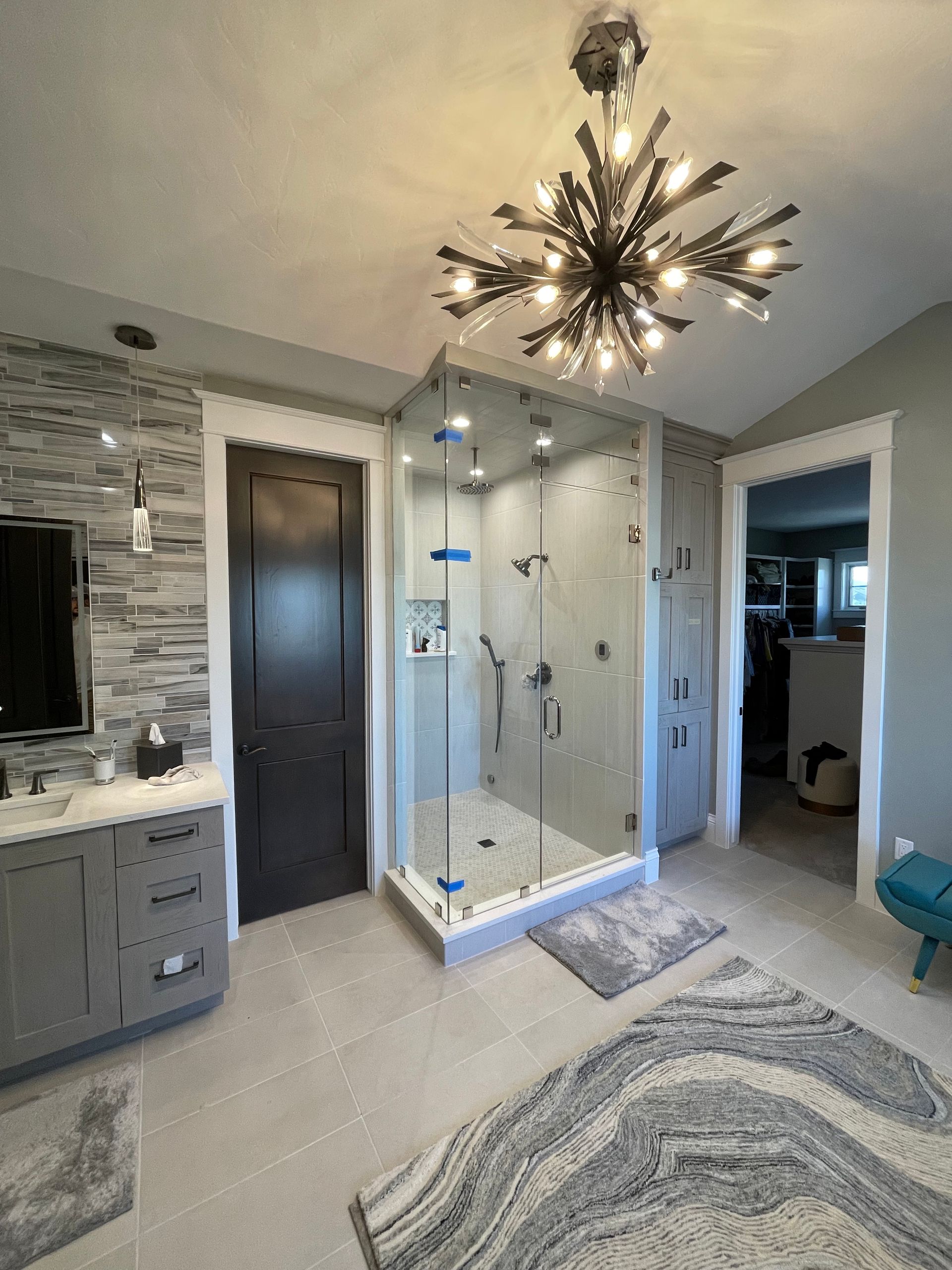 A bathroom with a walk in shower and a chandelier.