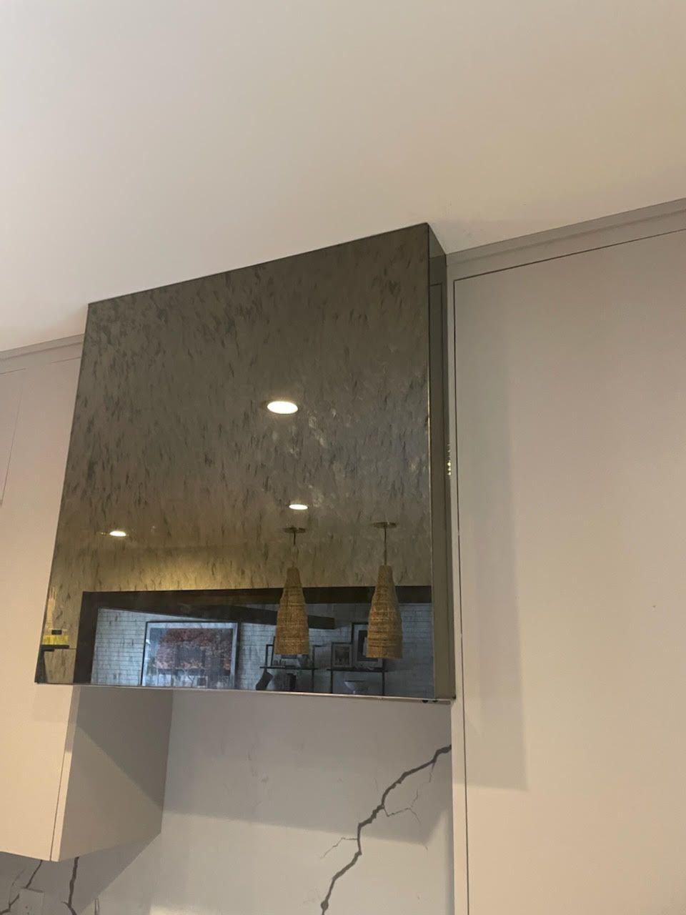 A kitchen with a stainless steel hood hanging from the ceiling.