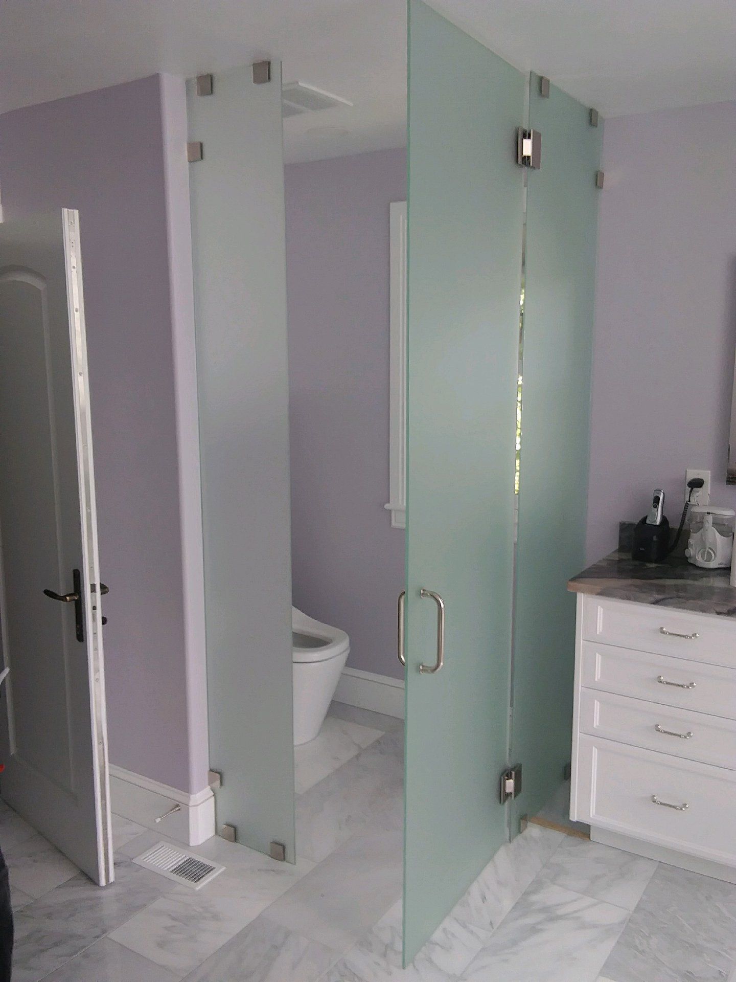 A bathroom with a toilet and a glass shower door.