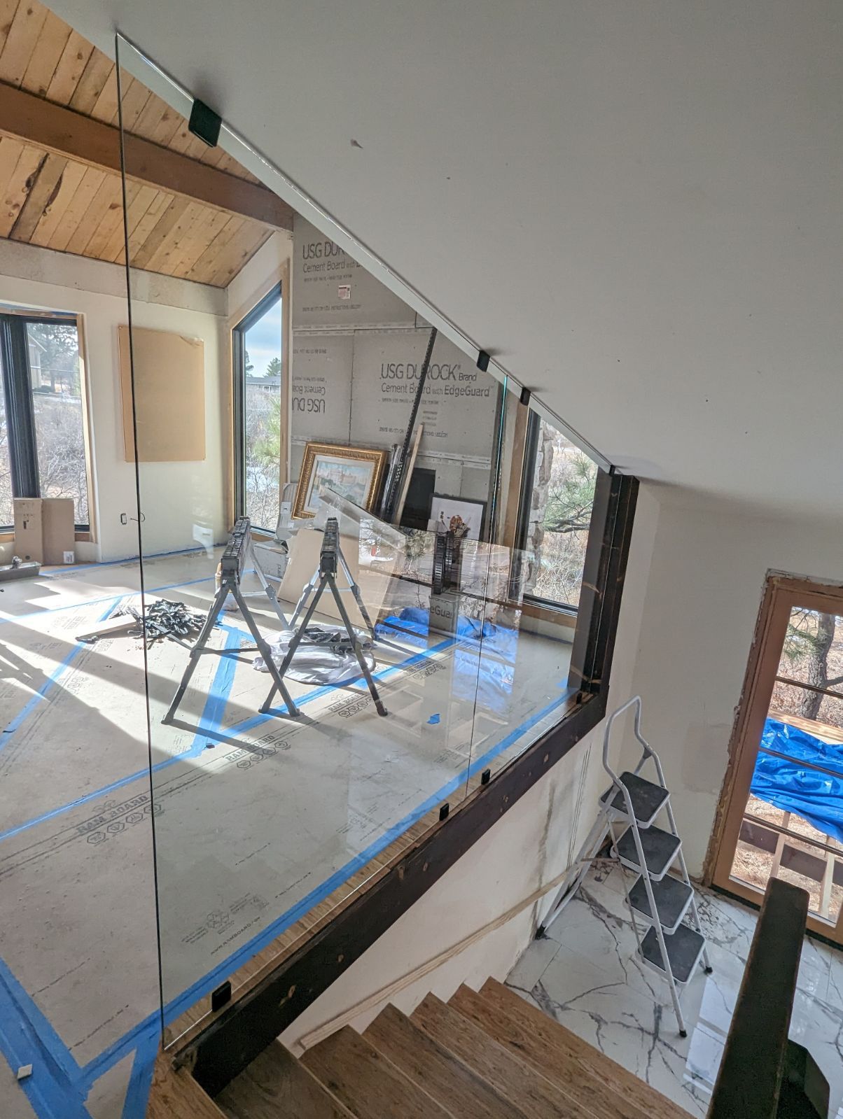 A staircase with a glass railing is being built in a house.