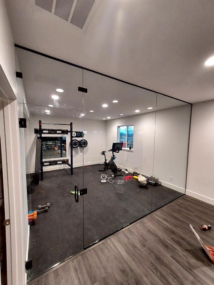 A home gym with a glass wall and a bicycle.