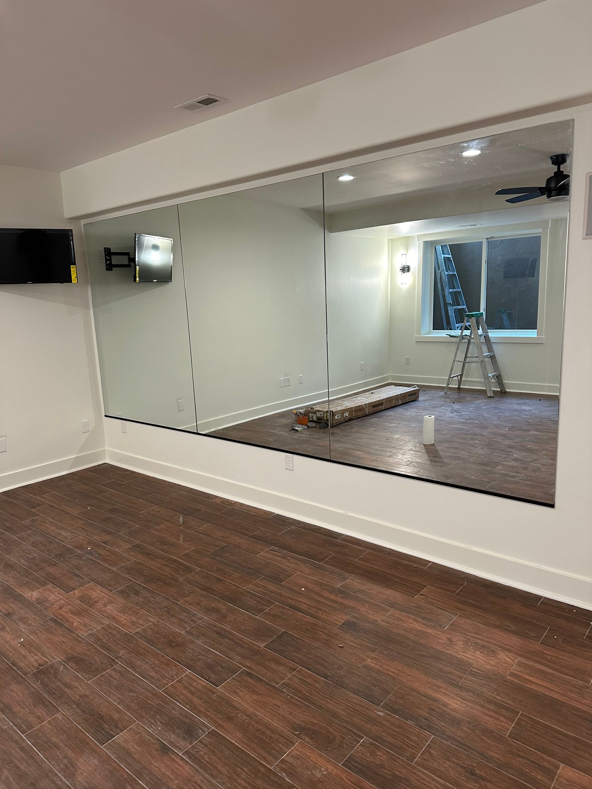 A room with a large mirror on the wall and a wooden floor.