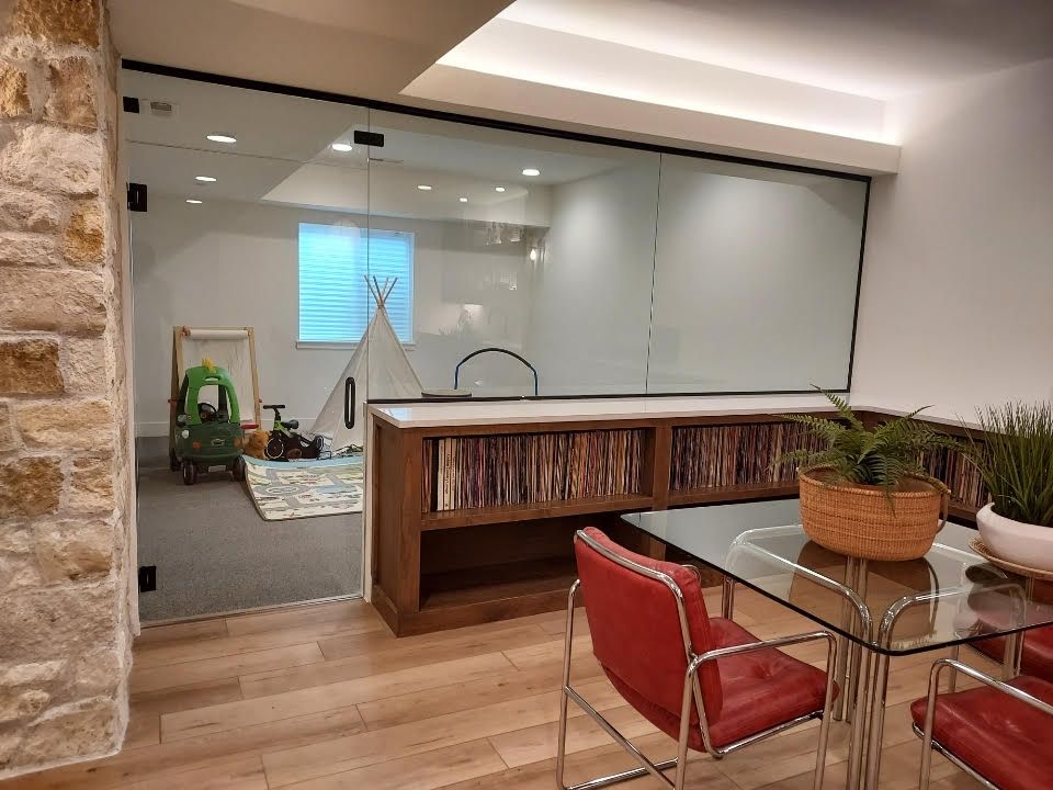 A dining room with a glass table and chairs and a bookshelf.
