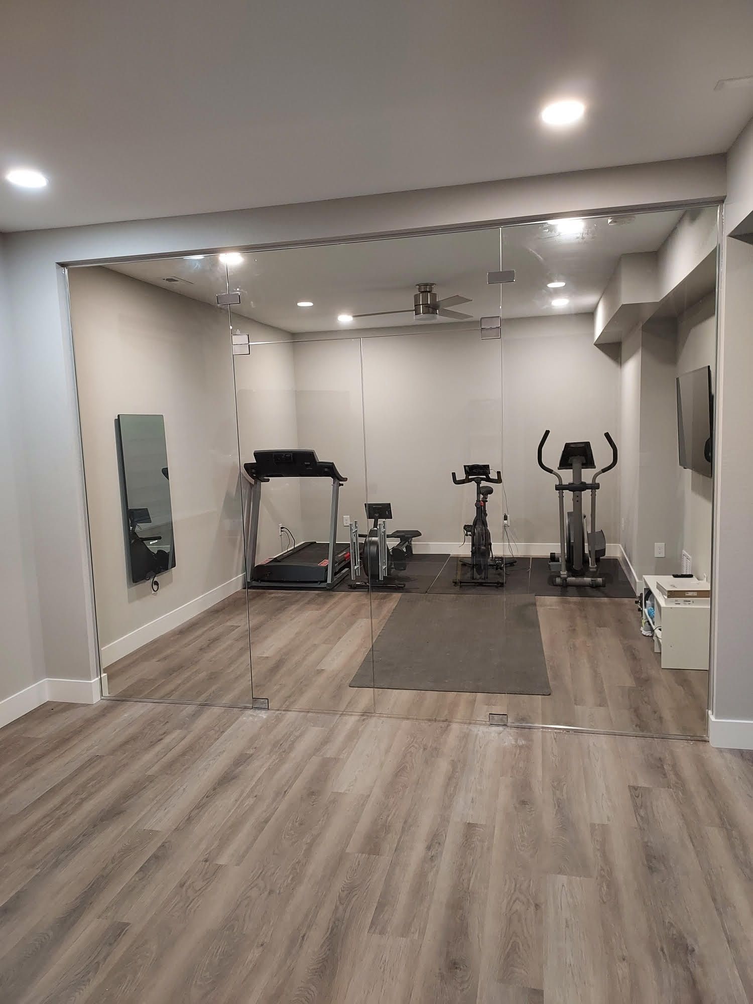 A basement gym with a treadmill , exercise bike , and mirror.