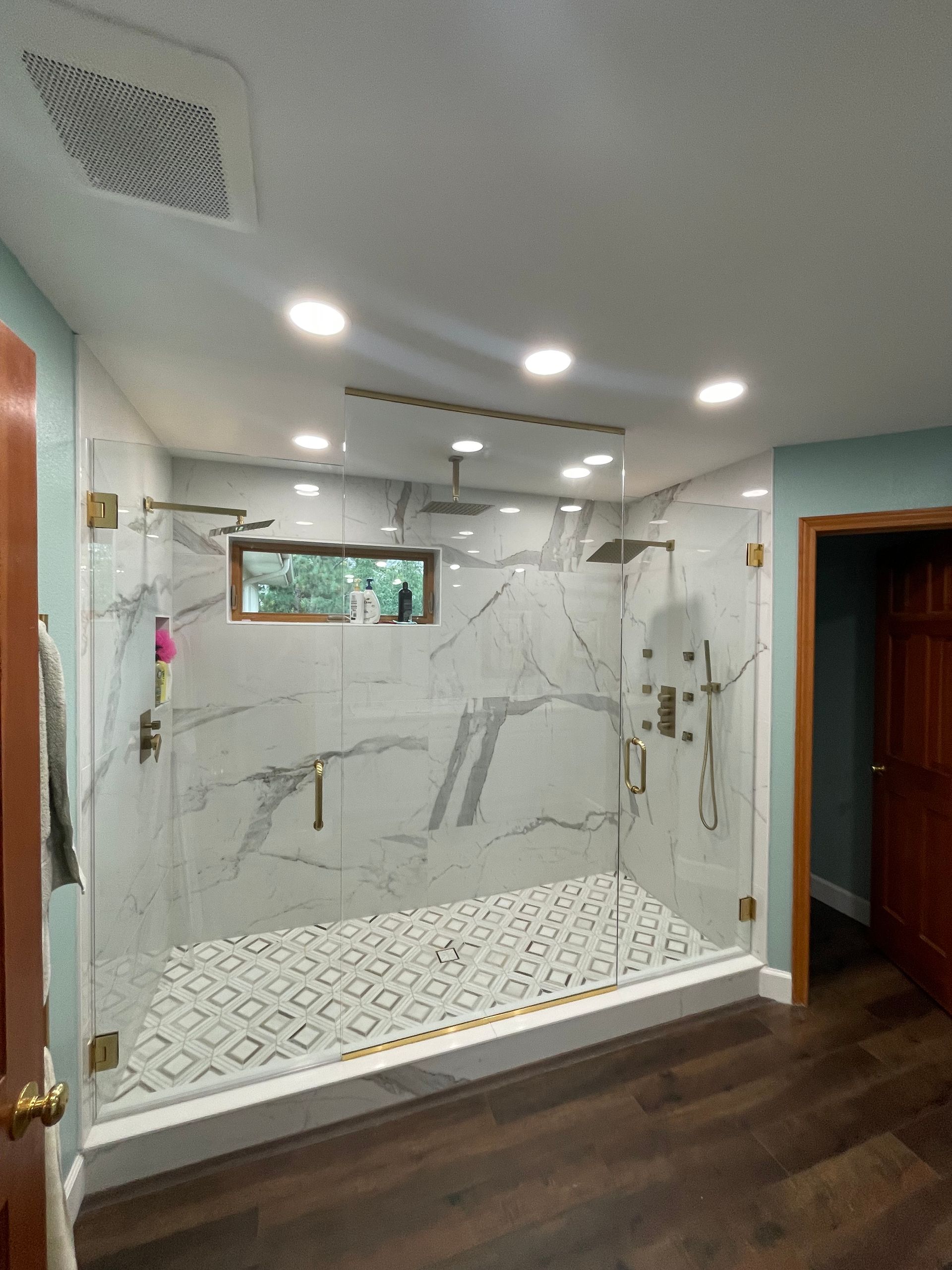A bathroom with a walk in shower and a window.