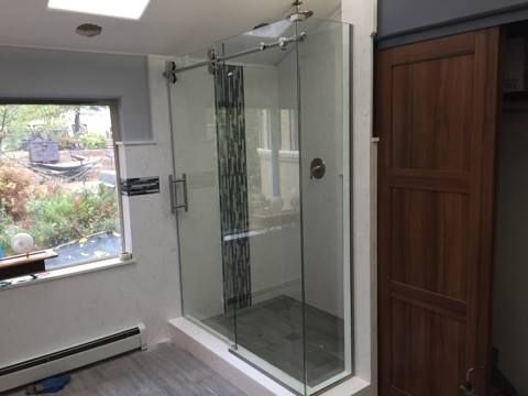A bathroom with a walk in shower and a window.