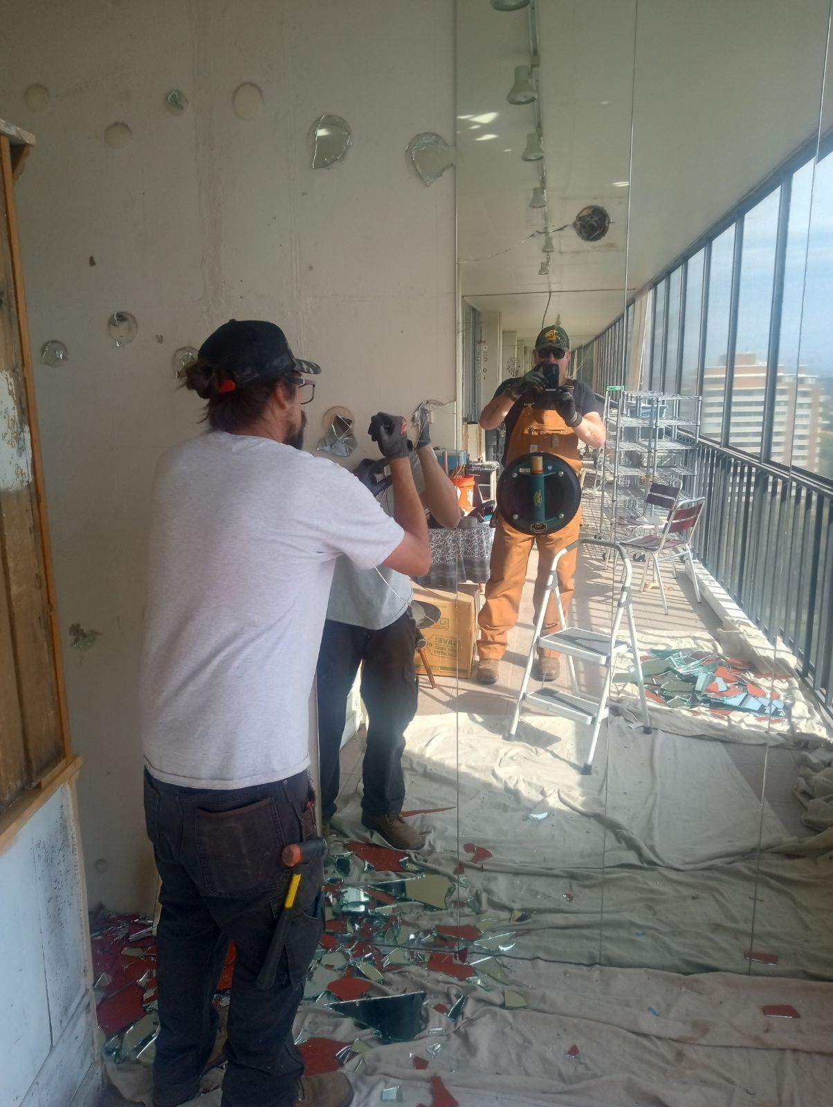A group of men are working on a large mirror on a balcony.