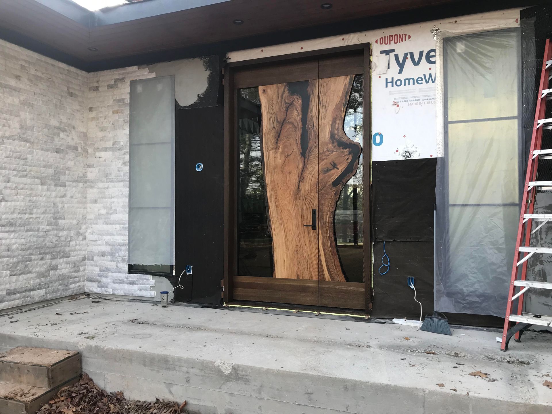 A large wooden door is being installed on the front of a house.