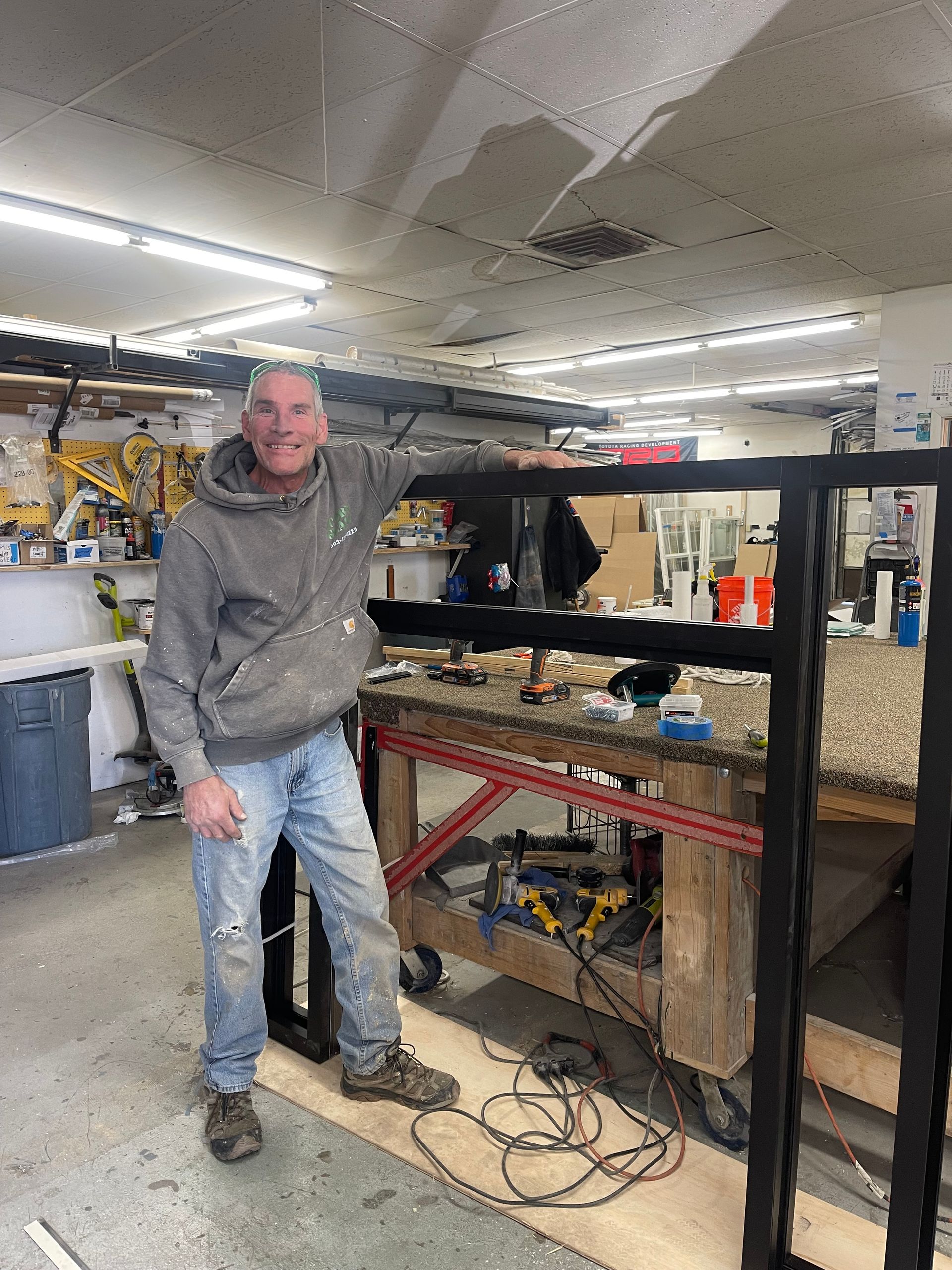 A man is standing in a workshop with his arms outstretched.