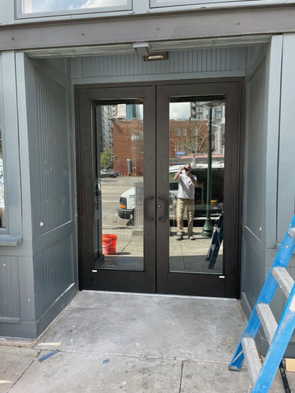 A man is standing in front of a door with a ladder in front of it