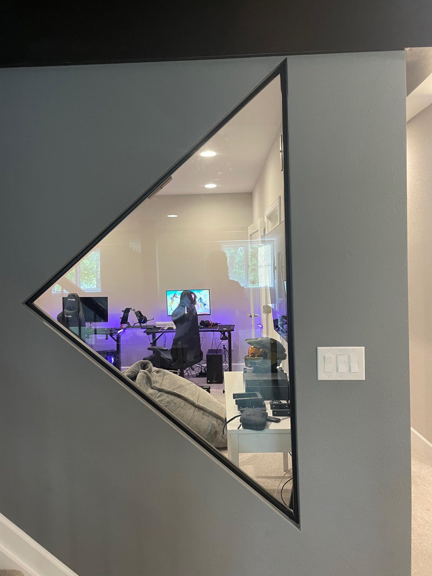 A person is sitting at a desk in a room with a triangle window.