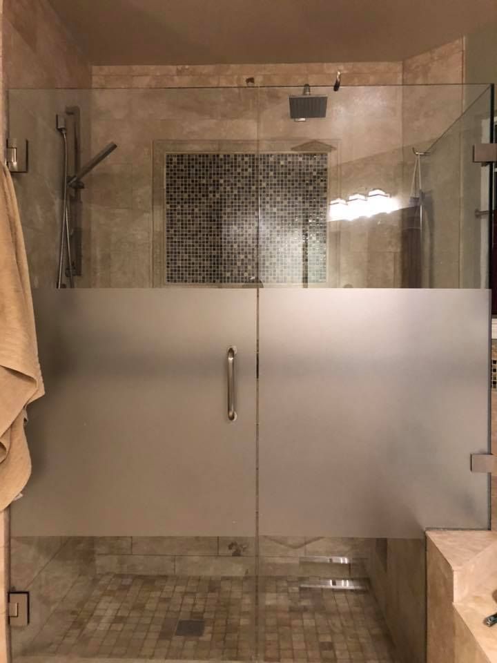 A bathroom with a walk in shower with a frosted glass door.