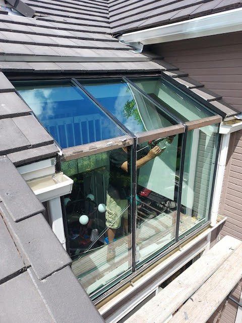 A man is cleaning a window on the roof of a house
