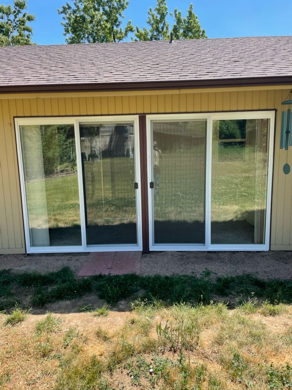 A house with sliding glass doors and a wind chime