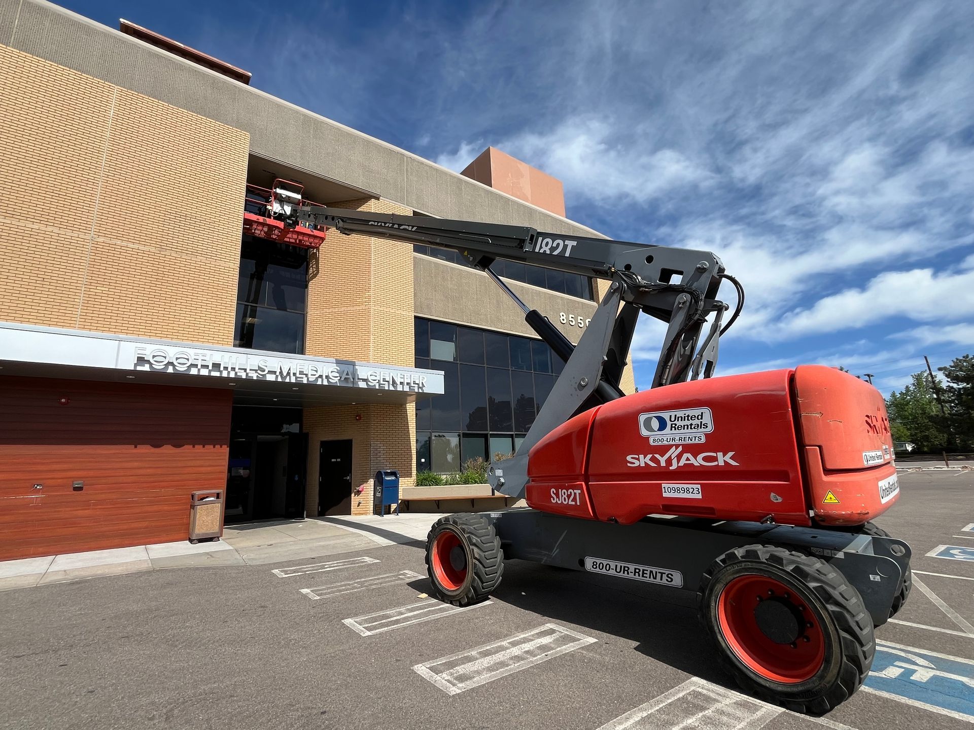 A red aerial lift is parked in front of a building.