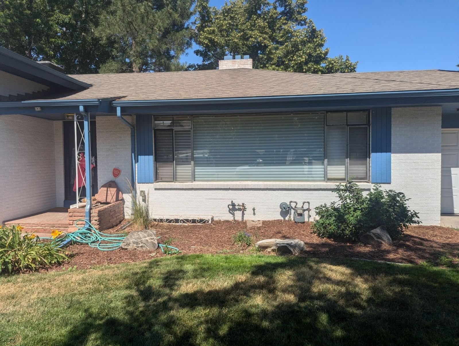 A white house with blue trim and a hose in front of it