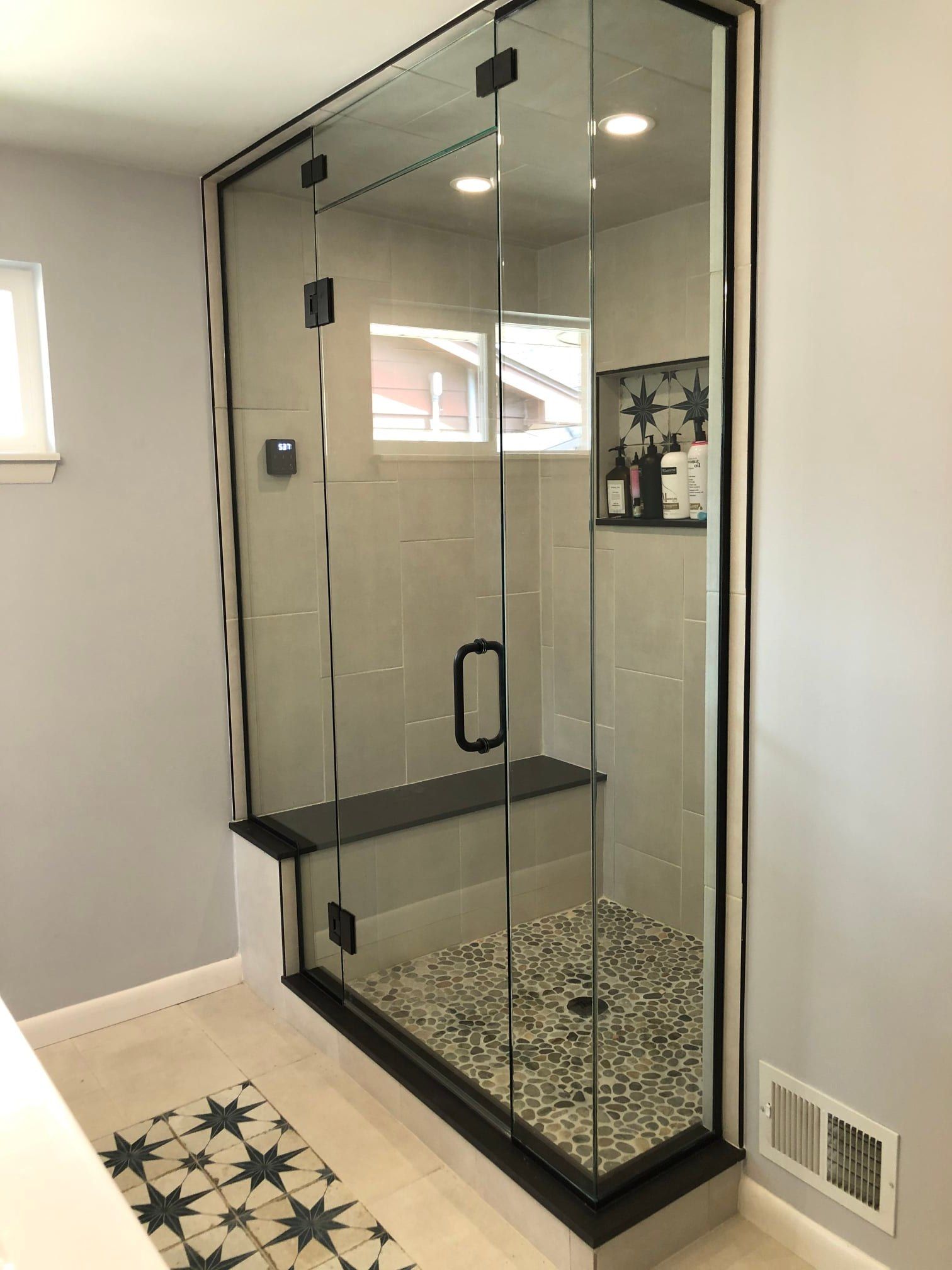A bathroom with a walk in shower with a glass door.