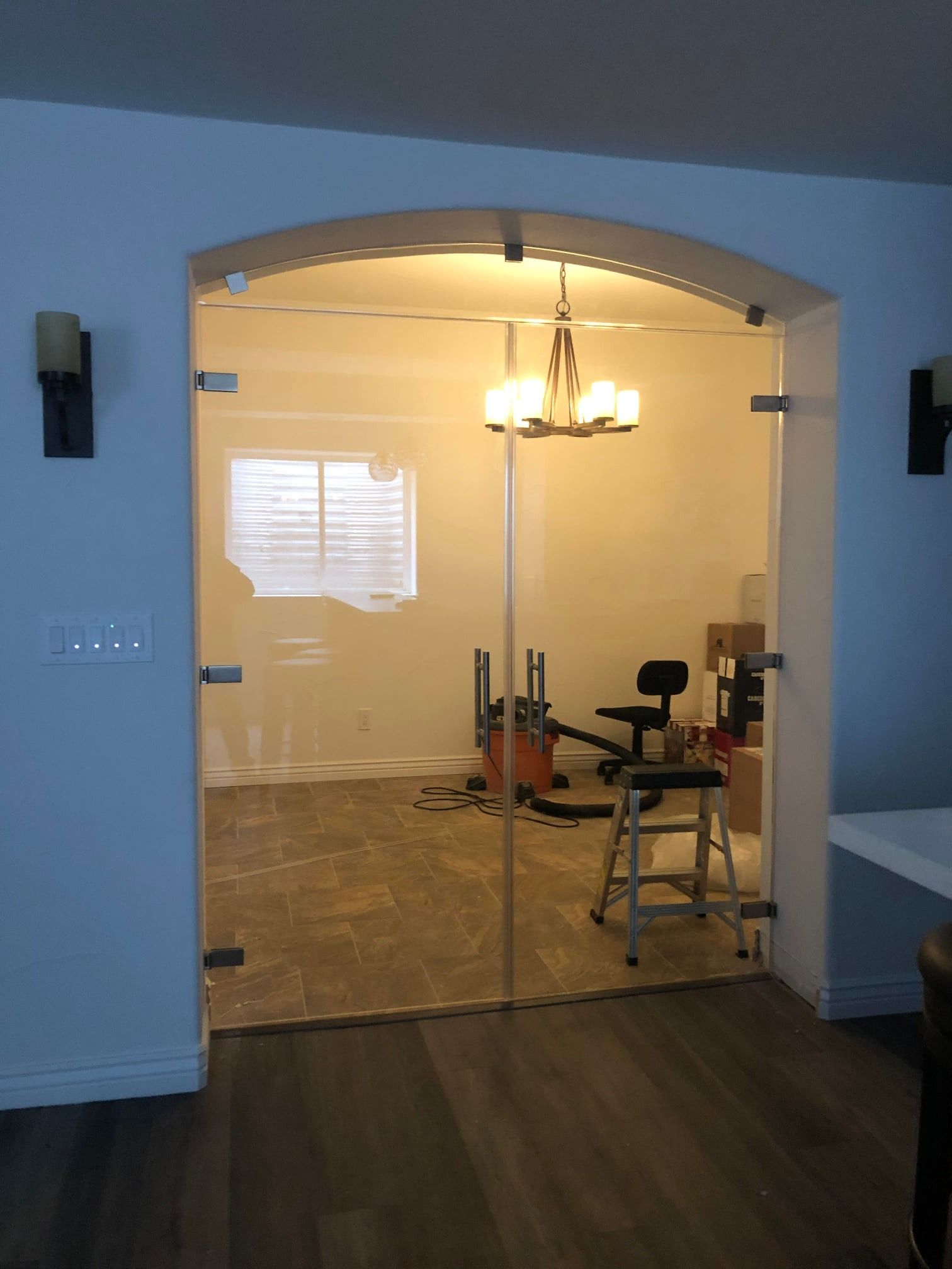 A room with a sliding glass door and a chandelier hanging from the ceiling.
