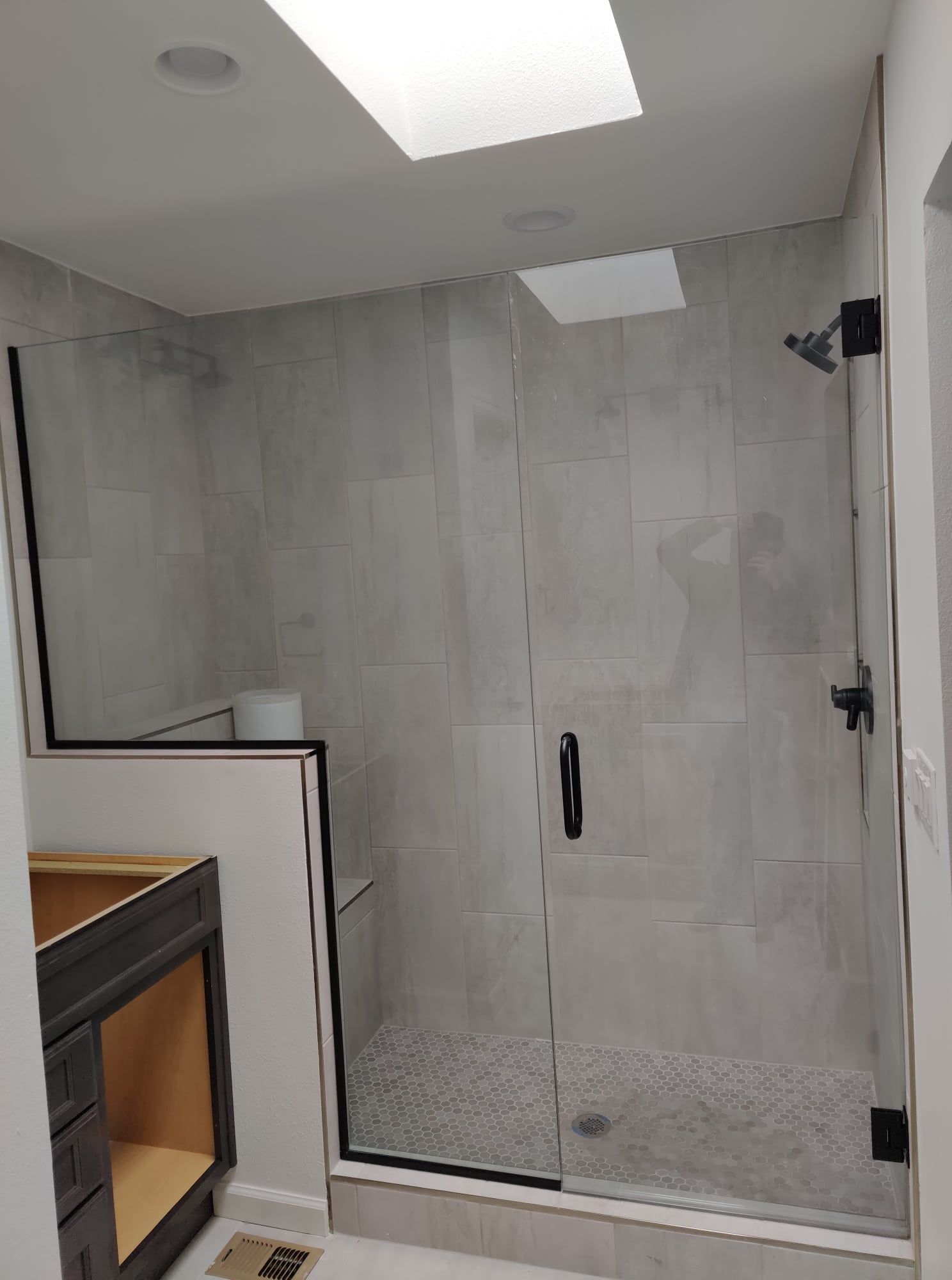 A bathroom with a walk in shower and a skylight.