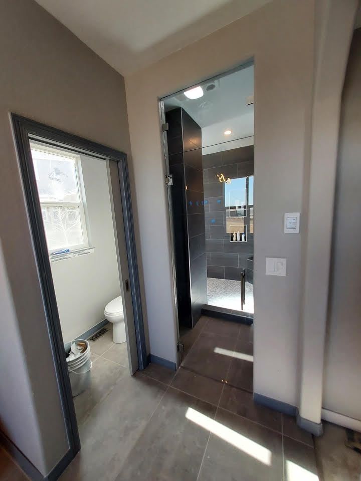A hallway leading to a bathroom with a toilet and a window