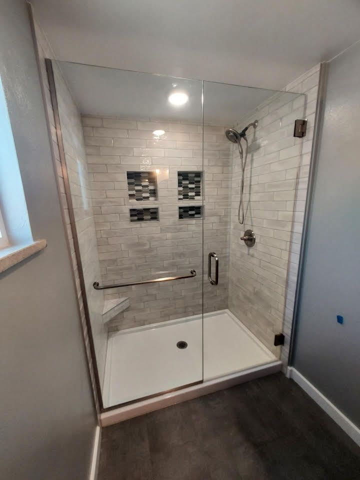 A bathroom with a walk in shower with a glass door.
