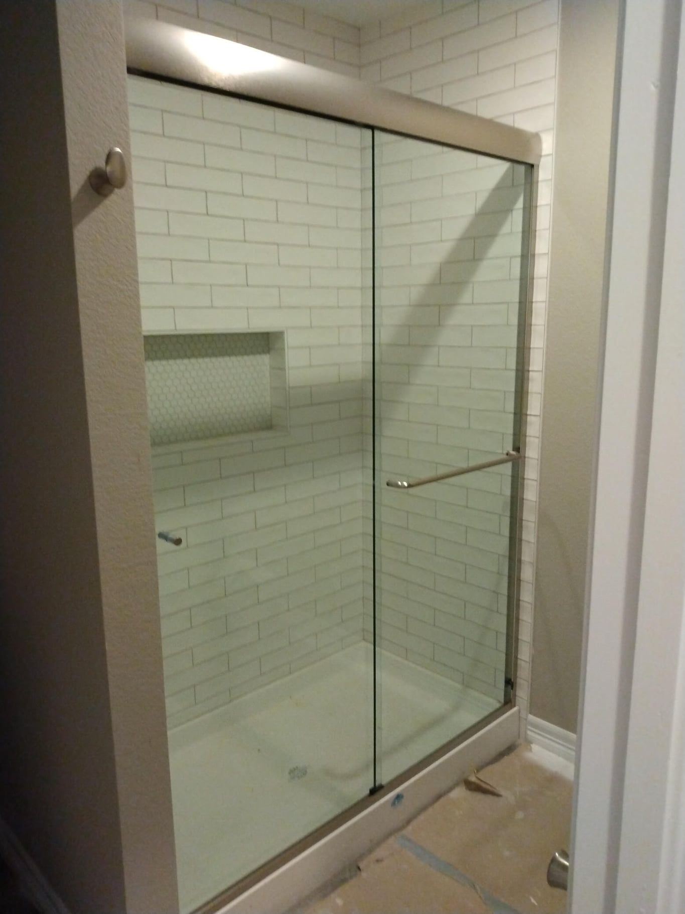 A bathroom with a sliding glass shower door and white brick walls.