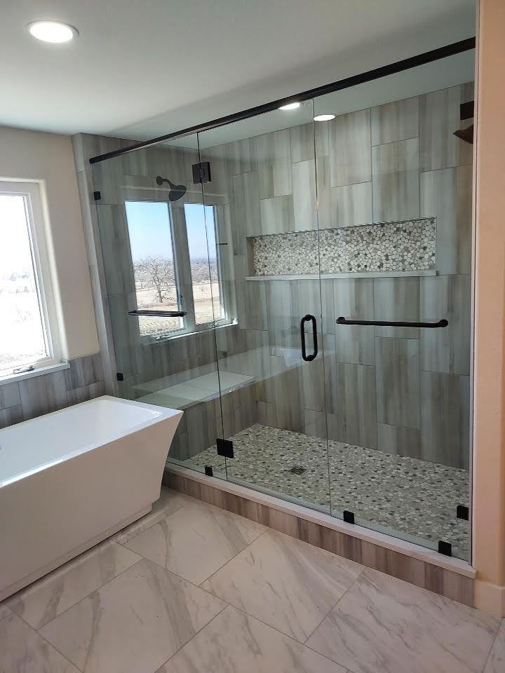 A bathroom with a bathtub and a walk in shower with a glass door.