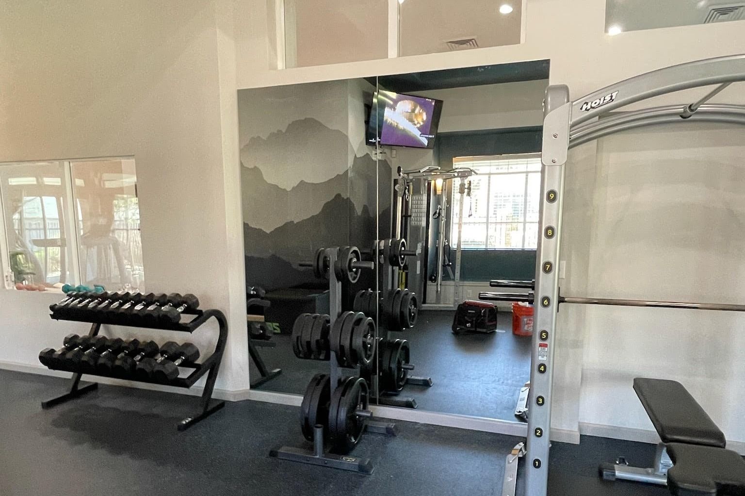 A gym with a lot of dumbbells and a tv on the wall.