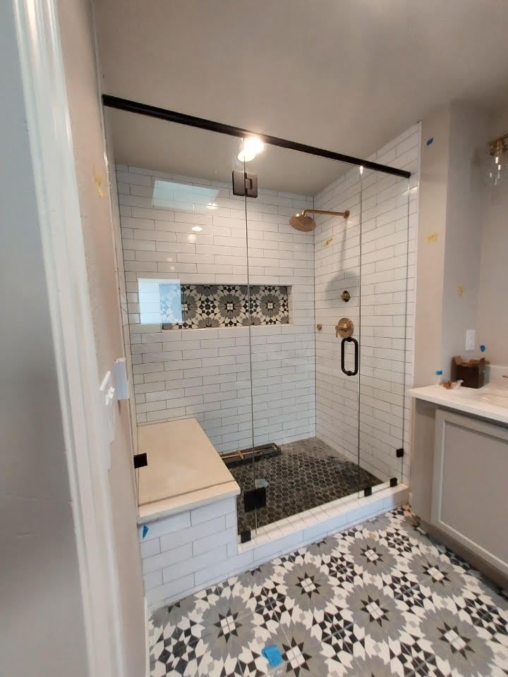 A bathroom with a walk in shower with a glass door.
