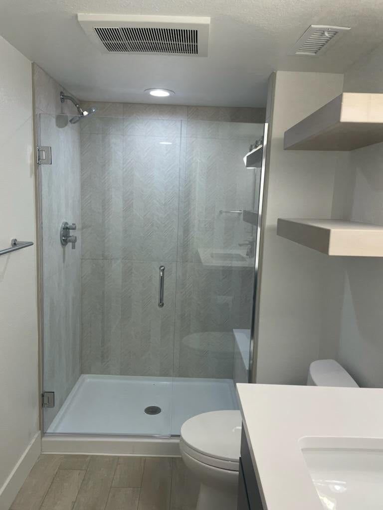 A bathroom with a toilet , sink and shower.