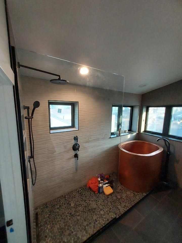 A bathroom with a walk in shower and a copper bathtub.