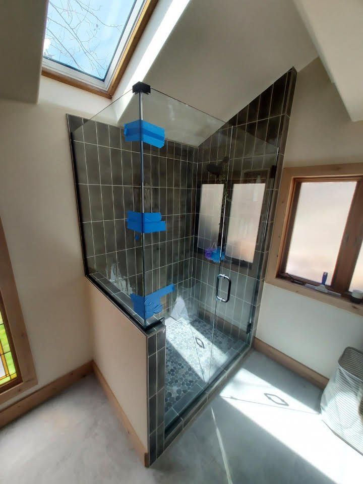 A bathroom with a glass shower door and a skylight.