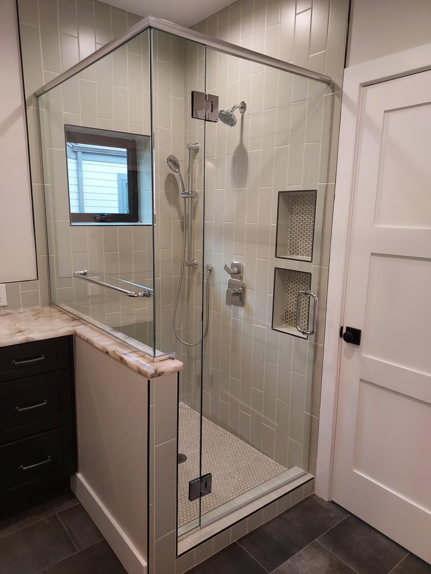 A bathroom with a walk in shower and a window.