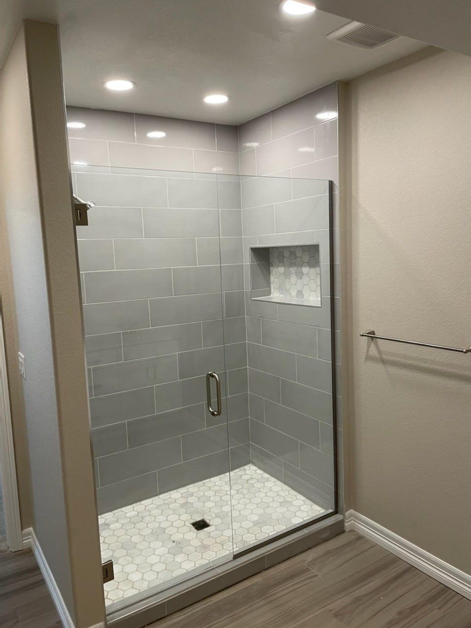 A bathroom with a walk in shower with a glass door.