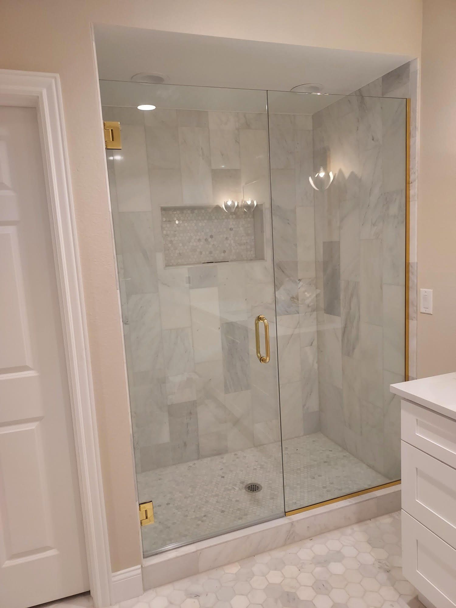 A bathroom with a walk in shower with a glass door.